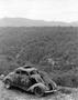 Photograph: [Abandoned car on a mountain roadside overlooking a forest]