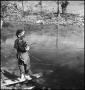 Photograph: [Photograph of a boy looking at the camera while fishing]